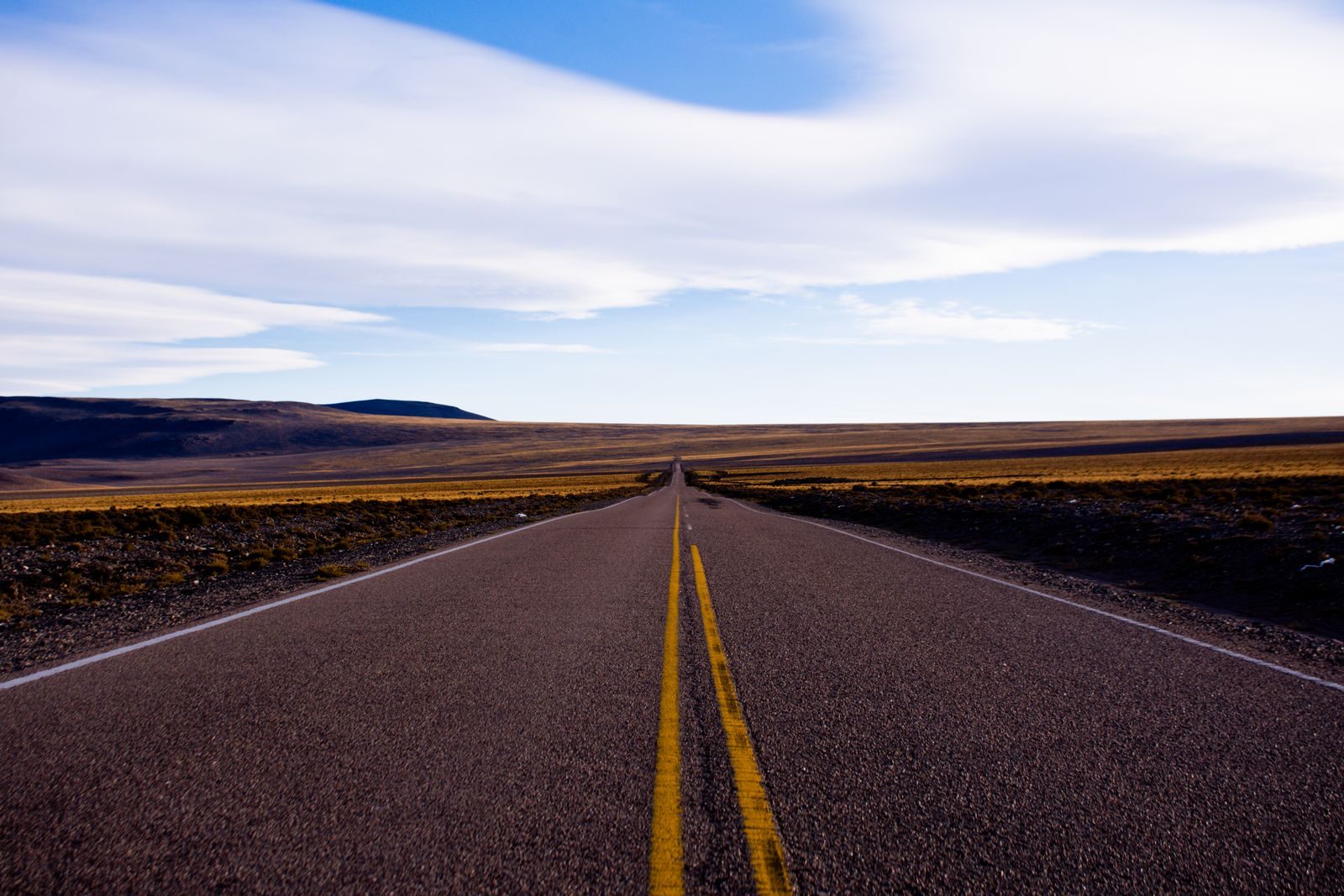 An empty two-lane highway running straight to the horizon